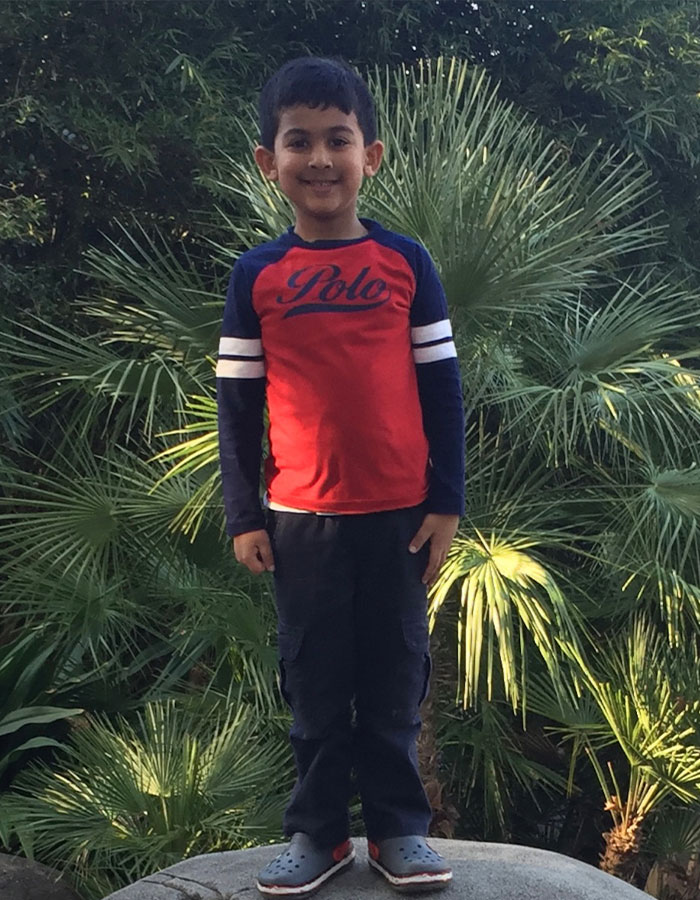 Smiling boy in a red and blue shirt stands in front of lush greenery, related to Netflix's 'Unsolved Mysteries. Smiling boy in a red and blue shirt stands in front of lush greenery, related to Netflix's 'Unsolved Mysteries.