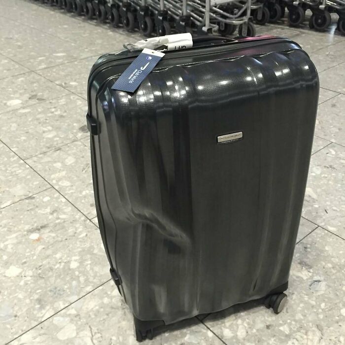 Dented suitcase on airport floor, showcasing an airline baggage fail.