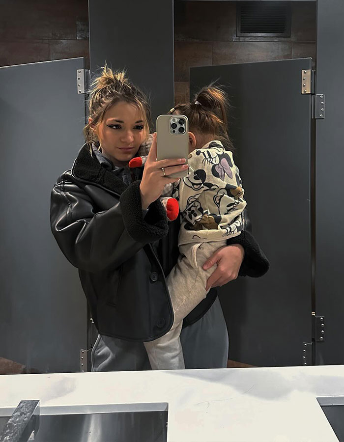Mom holding a child, taking mirror selfie in bathroom, highlighting "Rent A Private Jet" story context. Mom holding a child, taking mirror selfie in bathroom, highlighting "Rent A Private Jet" story context.