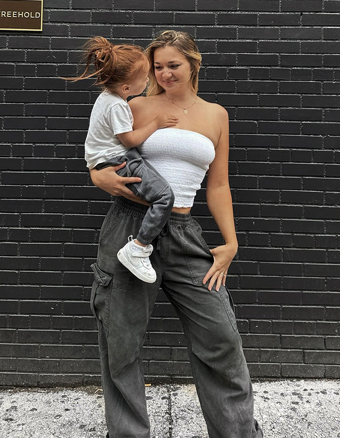 A woman holding a child against a black brick wall, related to renting a private jet discussion. A woman holding a child against a black brick wall, related to renting a private jet discussion.