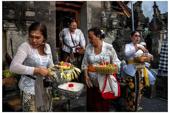 Women in traditional attire holding offerings, a raw street moment captured by Andrés Ramos.