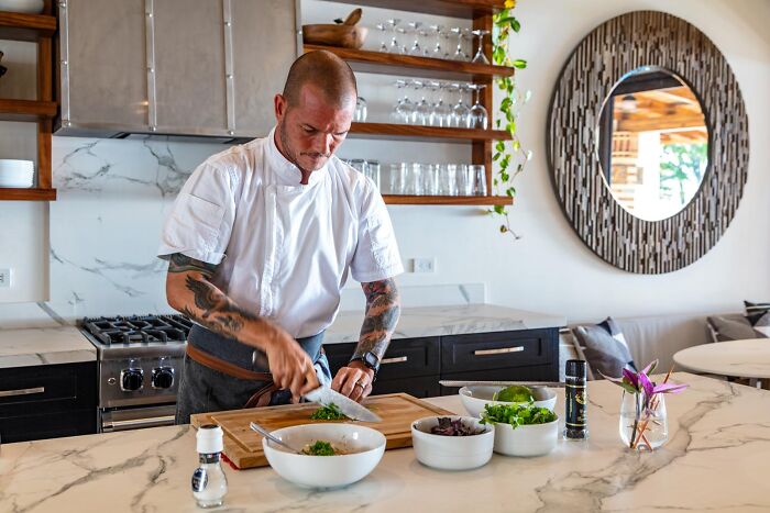 Chef preparing a meal in a luxury villa kitchen, showcasing superior vacation experiences beyond resorts.