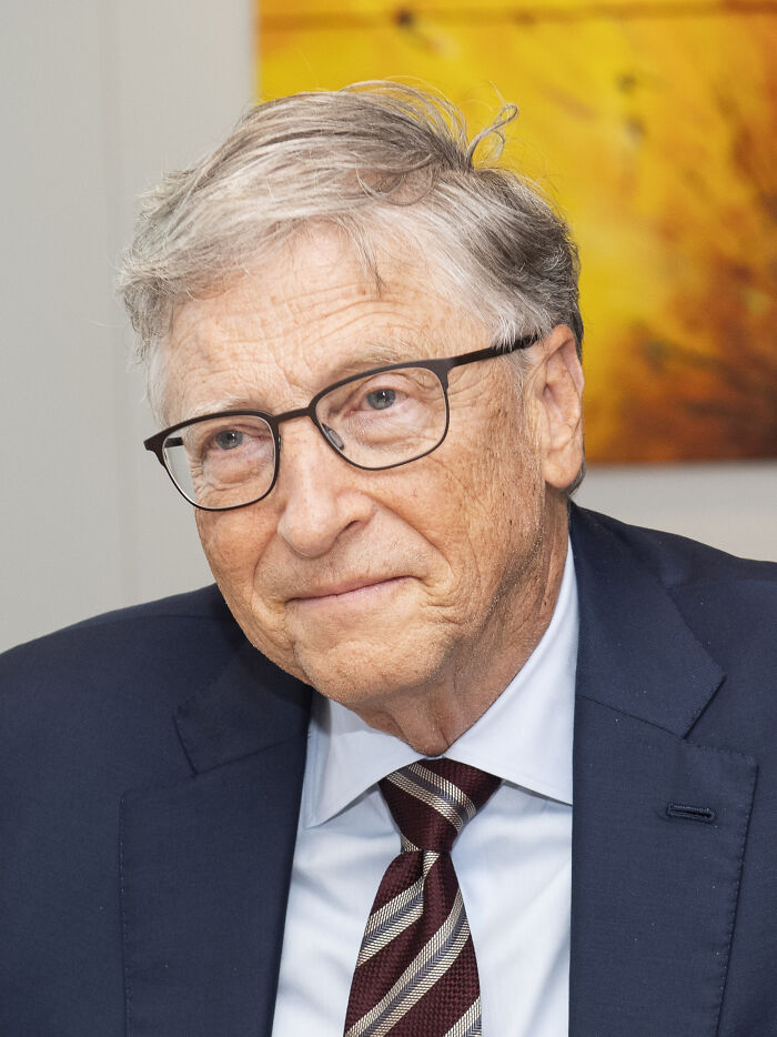 Older man with glasses in a suit and striped tie, representing one of the richest people with wealth surpassing most countries.