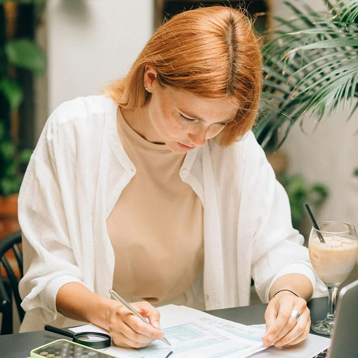 A woman writing at a desk with a pen, engaging in an entertaining and focused activity.