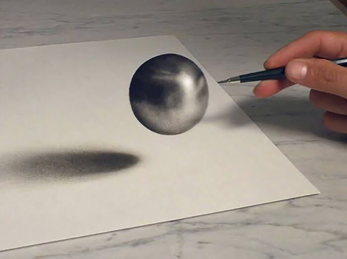 A hand with a pen creates a 3D drawing of a sphere with shadow, showcasing German artist's incredible skills.