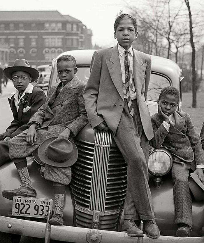 Boys in 1940s fashion sit on a vintage car, capturing historical moments vividly with Illinois license plate visible, 1941.