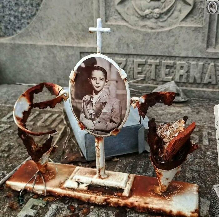 Young boy's headstone portrait in a rusted metal frame, featuring a black and white photo set against a weathered background.