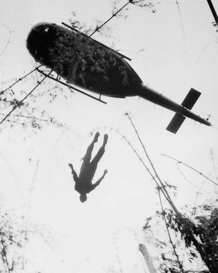 Silhouette of a person jumping from a helicopter, capturing a dramatic moment in historical aviation.