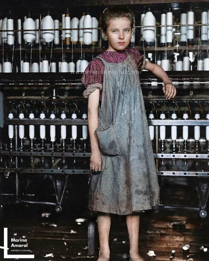 Young girl in historical clothing standing by a spinning machine, representing past industrial times.