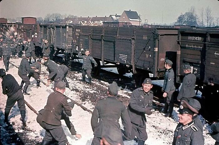 Historical picture of soldiers playfully tossing snowballs near a train in winter.