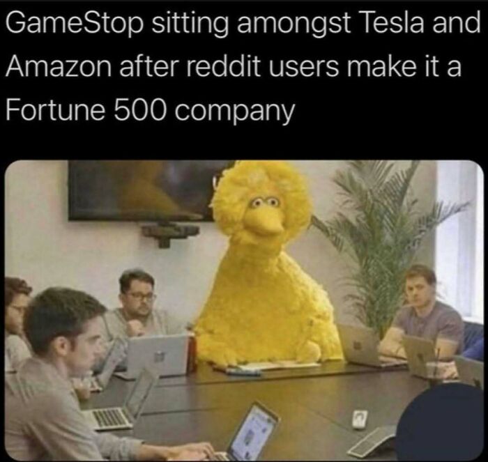 Big Bird humorously sits among serious office workers at a meeting, exemplifying work-related humor through a funny meme.