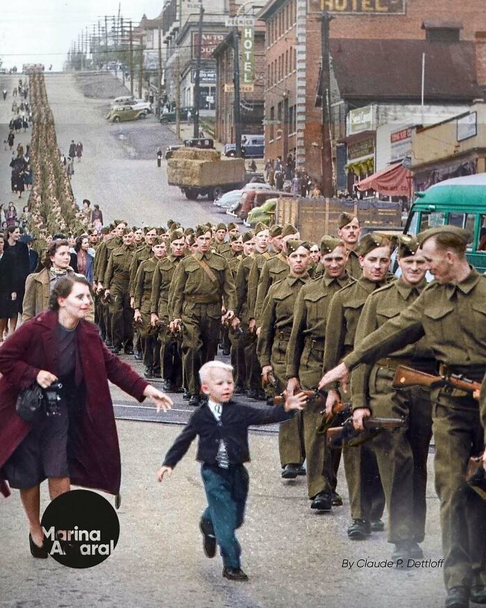 Child reaches for his father's hand in a historical World War II military march.
