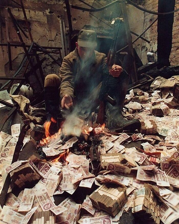 Soldier in rubble burning banknotes, highlighting historical struggles.