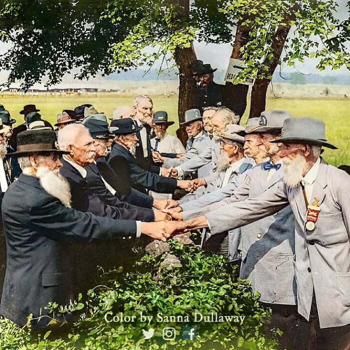 Veterans shaking hands at a historical reunion, showcasing significant moments from the past.