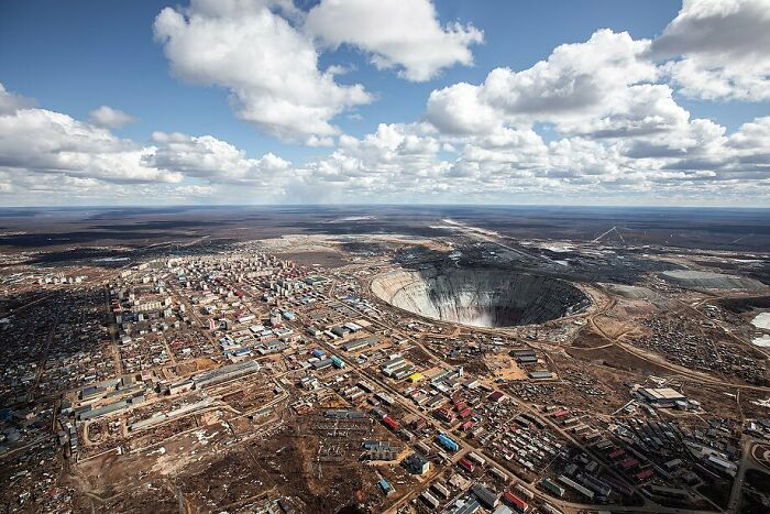 Aerial view of an iconic mining site with surrounding cityscape under a cloudy sky.
