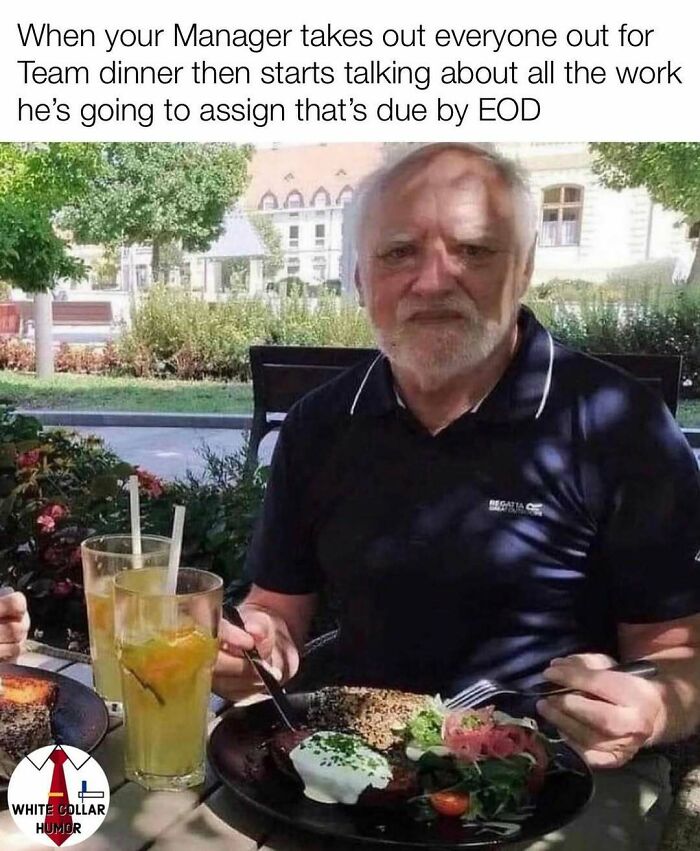 Man sitting at outdoor table with food and drinks, embodying work-related humor with an ironic expression.