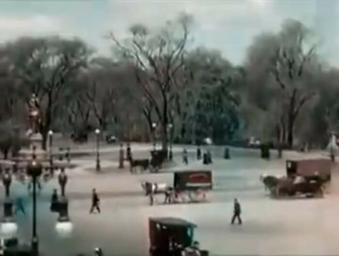 Vintage street scene with horse-drawn carriages and pedestrians, evoking nostalgia.