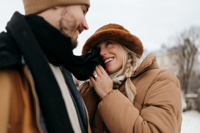 A couple in warm clothing shares a joyful moment outside, representing top engagement photos of 2025.