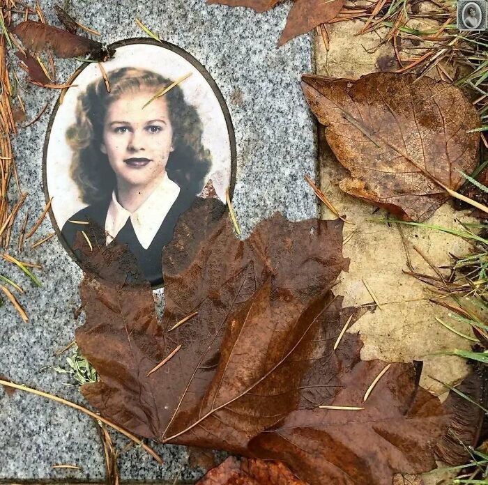 A lovely headstone portrait of a woman surrounded by autumn leaves on a granite surface.