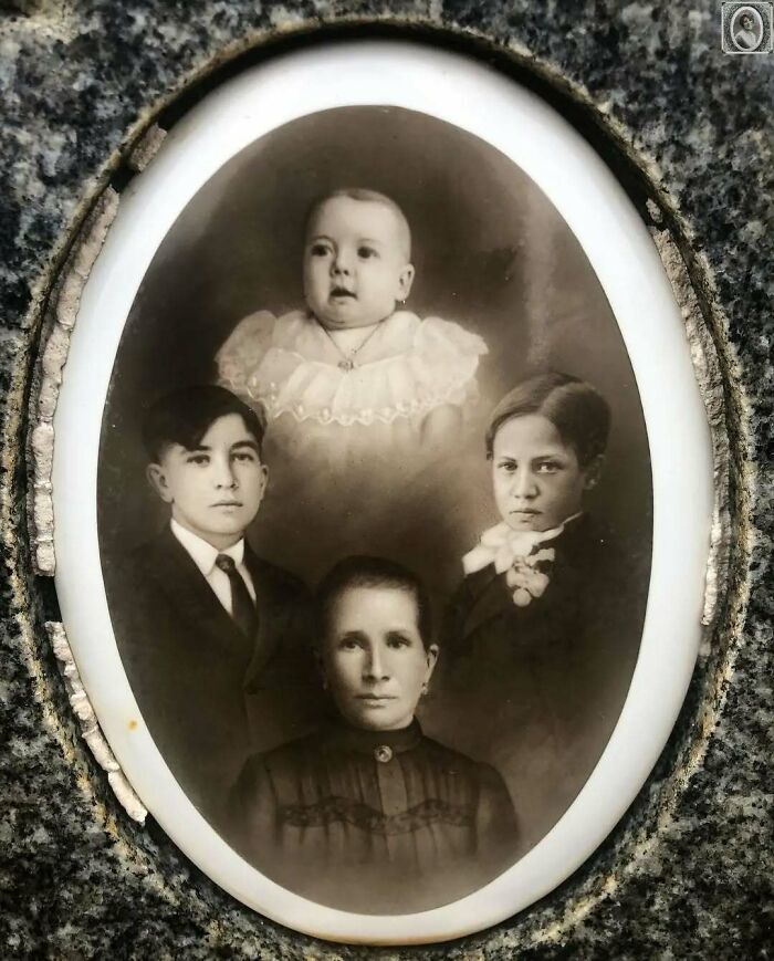 Vintage headstone portrait featuring a family with a baby and three children, set in an oval frame.