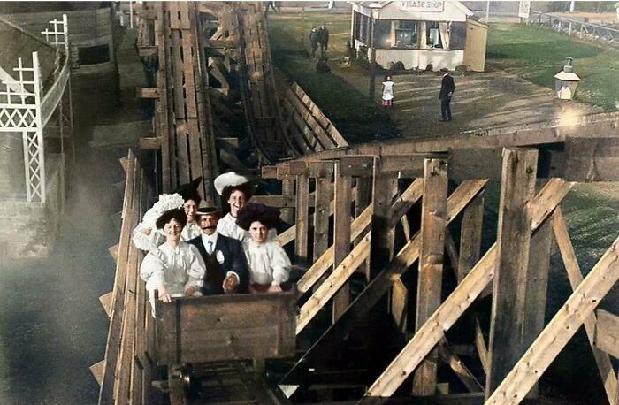People in vintage attire riding a wooden roller coaster, capturing historical nostalgia.