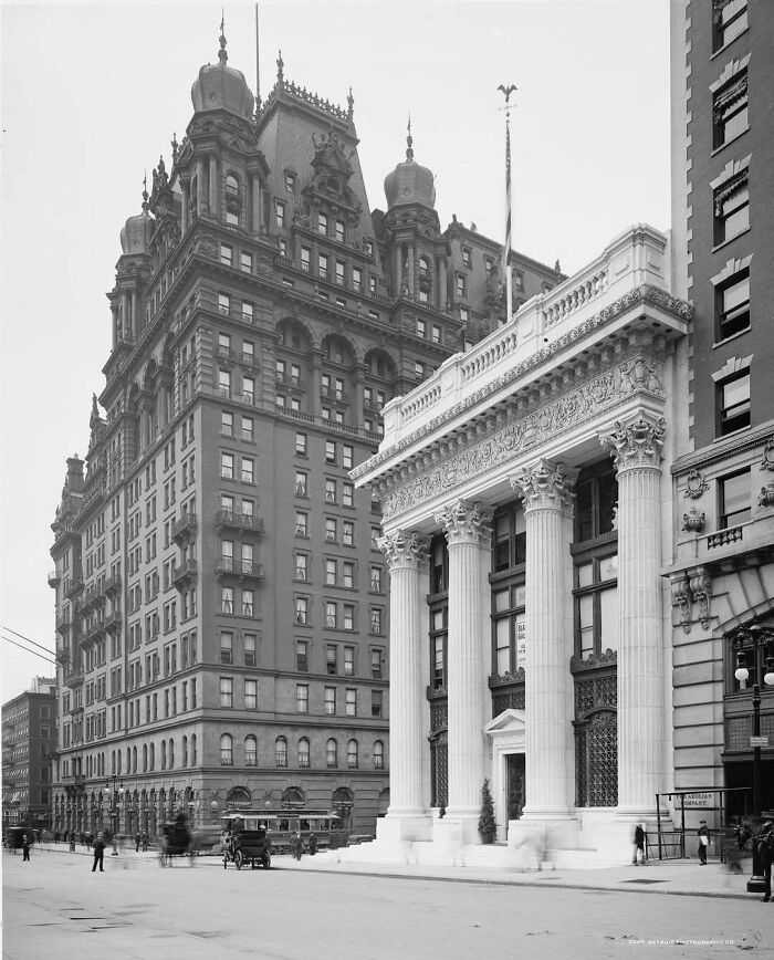 Historic American architecture featuring a grand building with ornate columns and a towering older structure beside it.