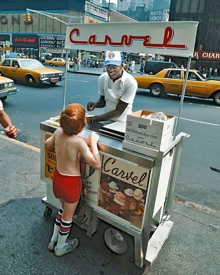 A nostalgic moment of a boy buying ice cream from a street vendor in a busy city scene.