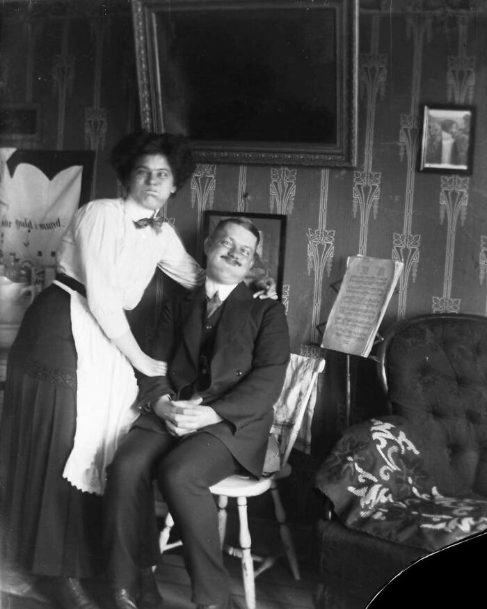 Historical photo of a woman and man in early 1900s attire, evoking nostalgia in a decorated room.