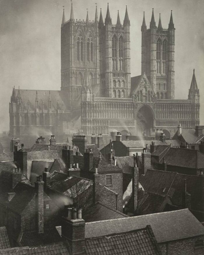 Historical photo of a majestic cathedral towering over old rooftops, capturing nostalgic architecture.