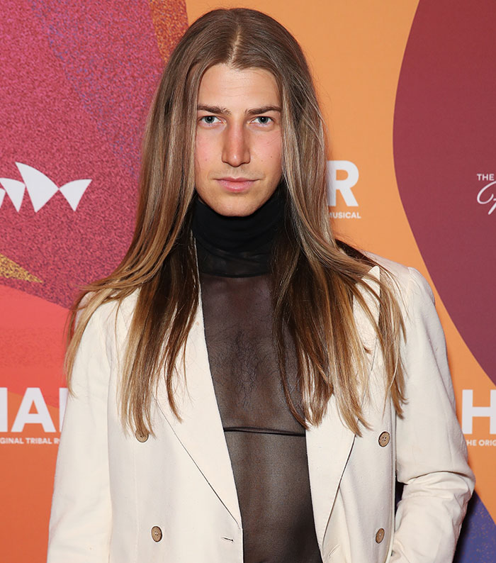 Richard Wilkins' son showcasing dramatic transformation in stylish attire at an event backdrop.