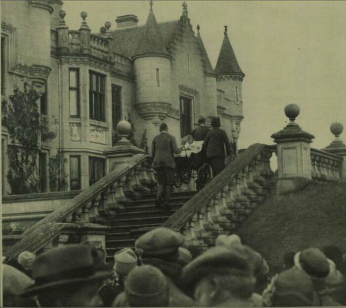 Historical scene of people ascending ornate stairs at a castle, evoking nostalgia.