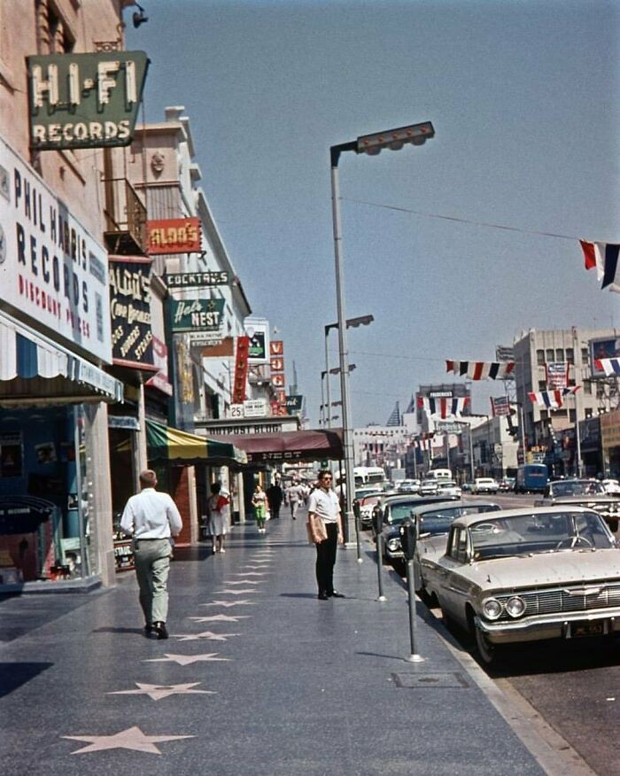 Historical street scene with classic cars and vintage signs, capturing nostalgia on a bustling city sidewalk.