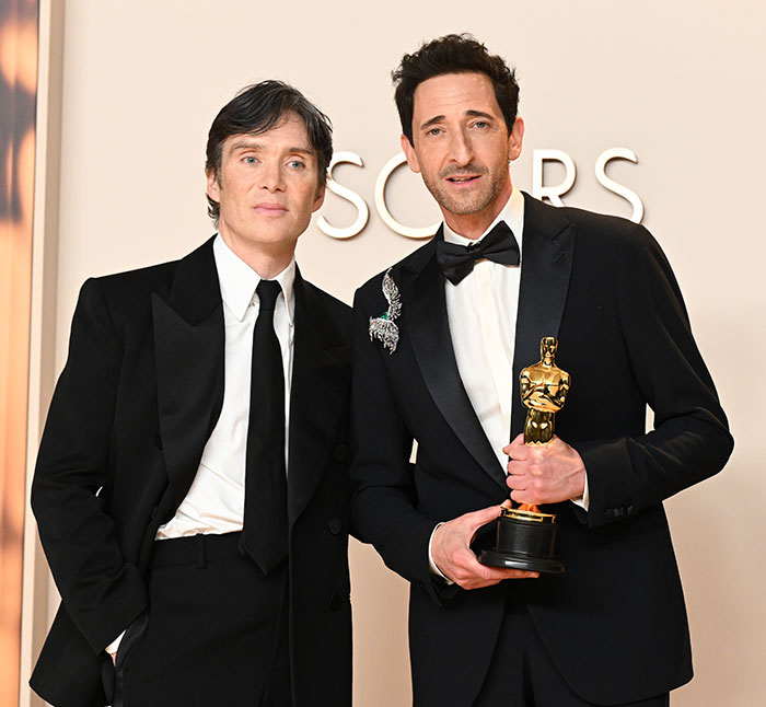 Cillian Murphy at the Oscars with Adrien Brody holding an award.