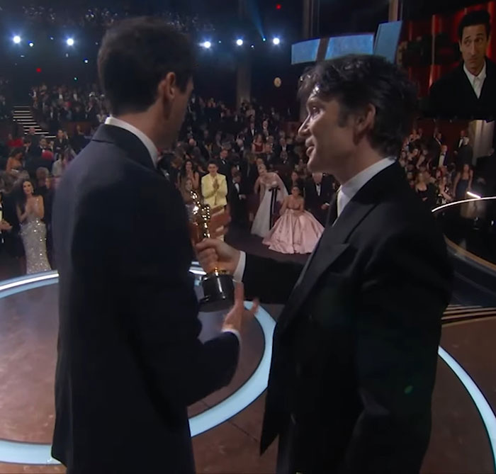 Cillian Murphy looks on as Adrien Brody holds Oscar, making headlines for his expression during the event.