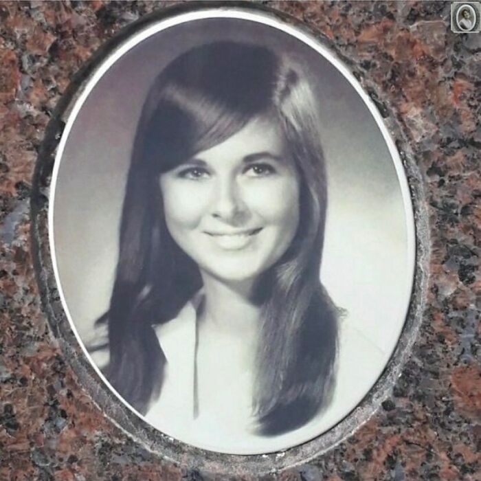 Lovely headstone portrait of a smiling woman with long hair, set in an oval frame on a granite surface.