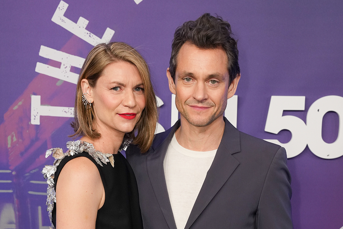 Claire Danes and Hugh Dancy posing together on the red carpet, featuring elegant evening attire against a purple backdrop.