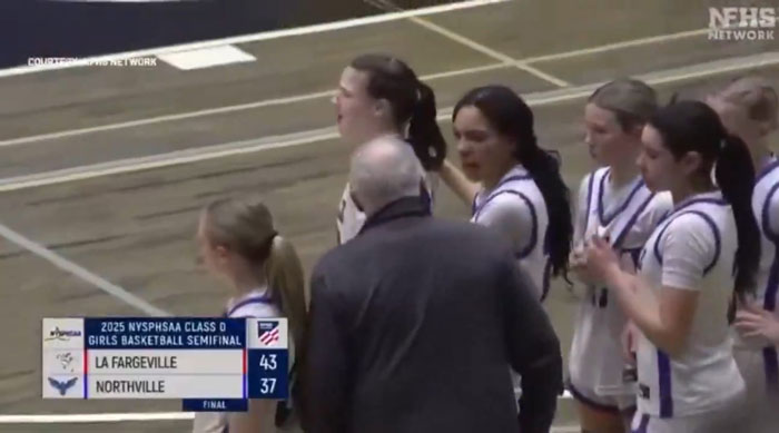 High school basketball coach with team during semifinal game, scoreboard showing La Fargeville leading Northville.