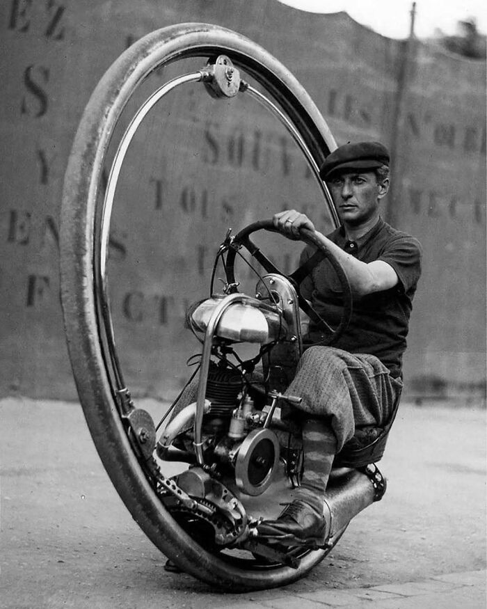 Man riding a vintage monowheel, showcasing unique historical transportation from the past.