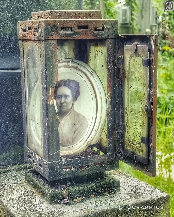 Old headstone portrait in a rusted frame, depicting a Victorian woman in a garden setting.