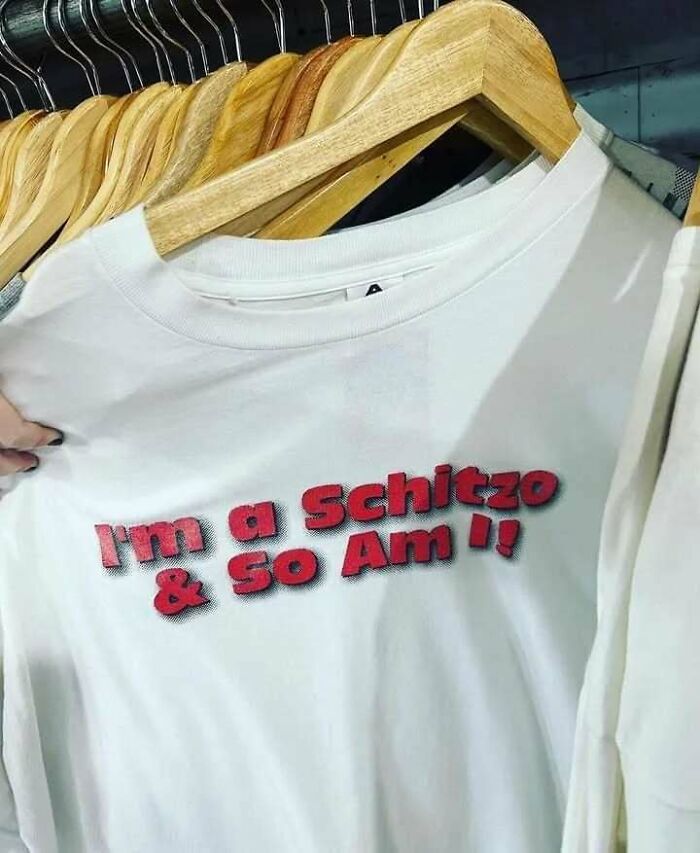 White T-shirt with humorous chaotic text in red lettering on a hanger.