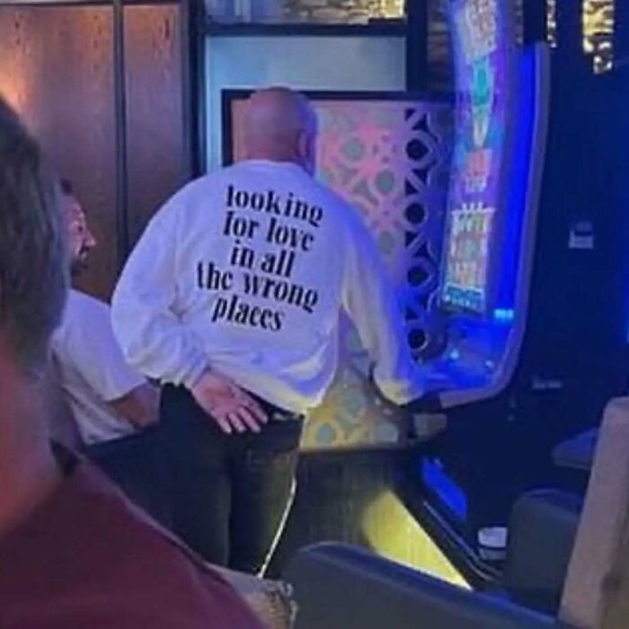 Man in a casino wearing a chaotic T-shirt that reads "looking for love in all the wrong places."
