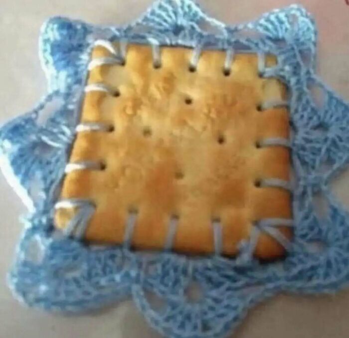 Square cracker sewn with blue yarn, resembling chaotic food creativity.