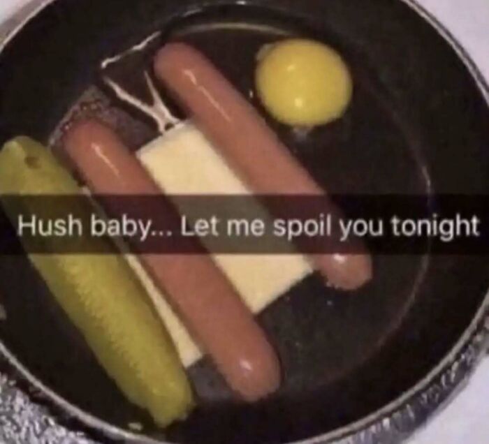 A chaotic plate with hot dogs, cheese, a pickle, and an egg yolk, captioned humorously.