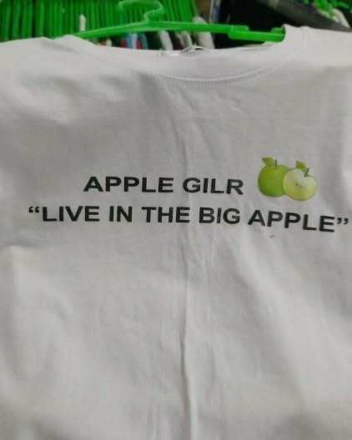 White T-shirt with text "APPLE GIRL LIVE IN THE BIG APPLE" and two green apples, showcasing chaotic humor.