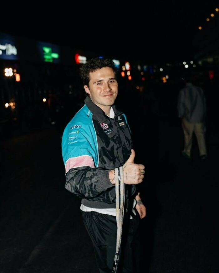 Person in a sporty jacket gives a thumbs-up at a night event, representing not-self-made-celebs theme.