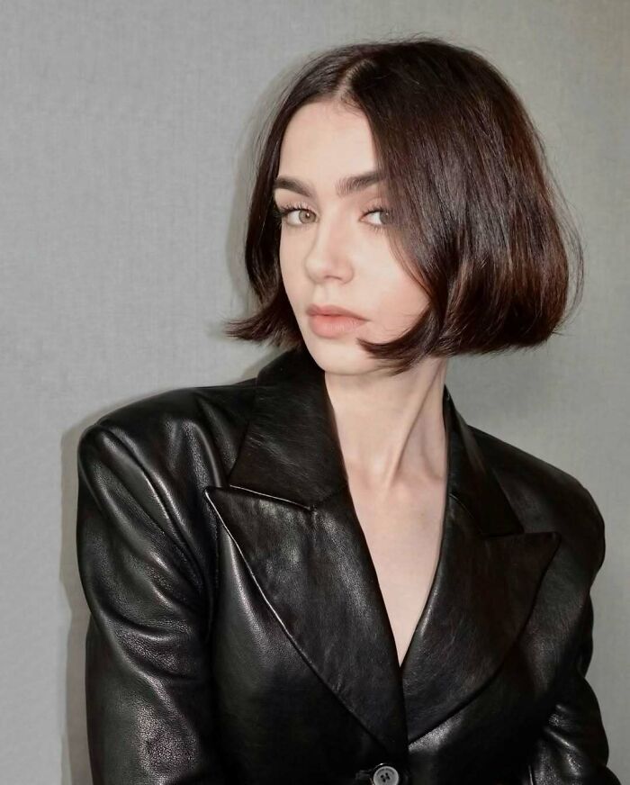 Young woman in a black leather jacket, embodying not-self-made-celebs style in a poised, elegant pose.