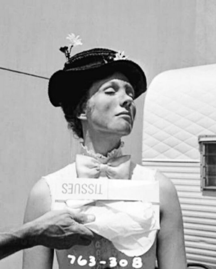 A woman with a bow tie holding tissues in a vintage setting, evoking a historical photo atmosphere.