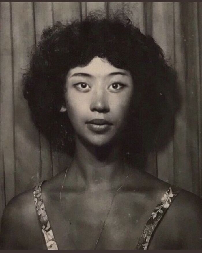 Vintage portrait of a woman with curly hair and patterned dress, showcasing historical fashion.