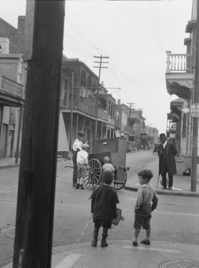 Children gather around a street vendor's cart, capturing a historical moment in an old neighborhood.