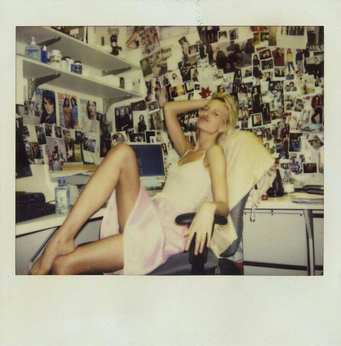 Young woman poses in a cluttered office space full of photos, offering a fascinating glimpse into the past.